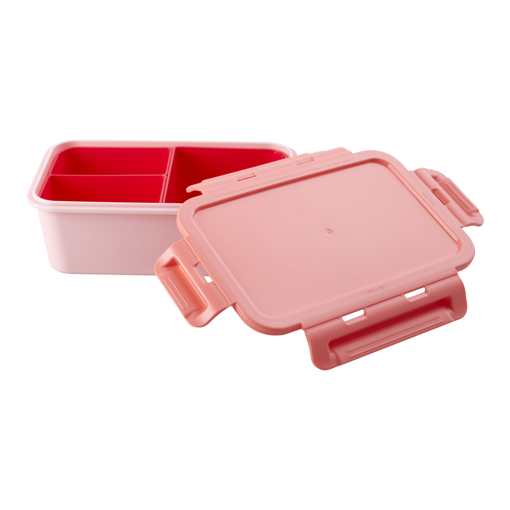 Large square pink bento lunch box from Rice with its coral clip lid open beside three red compartment inserts