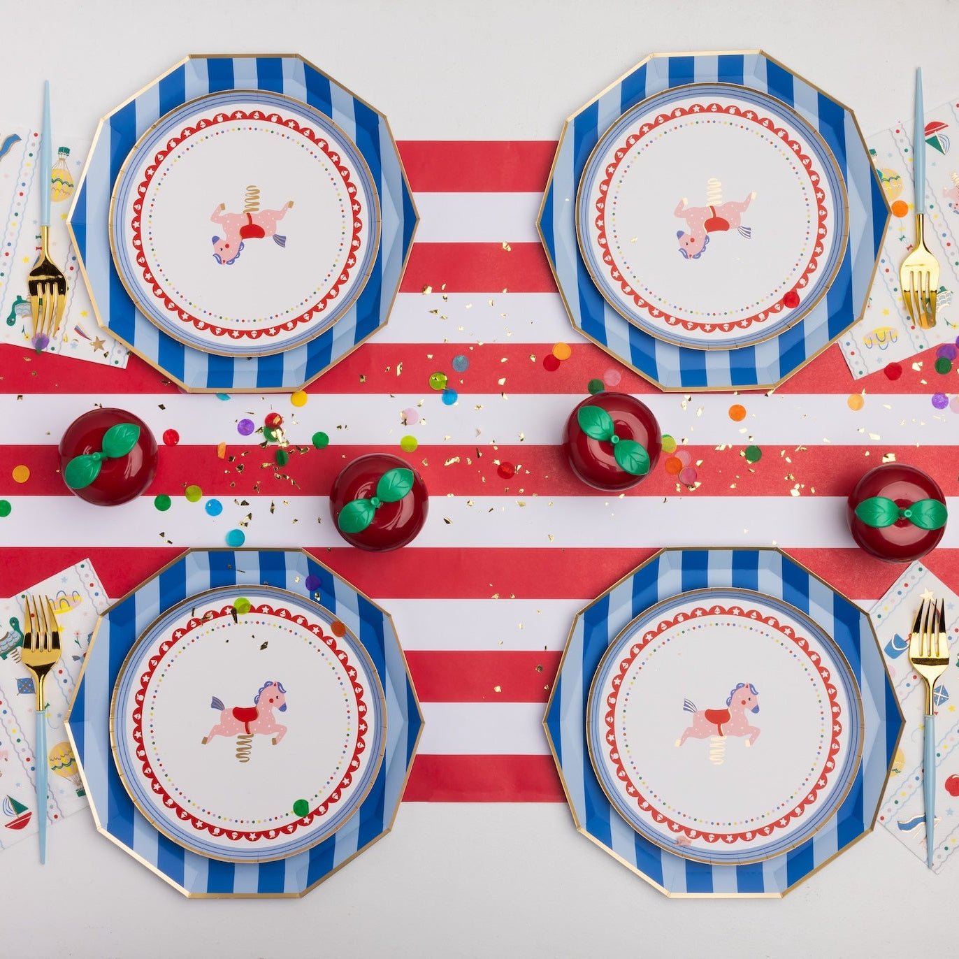Petite playground carousel horse plates layered on blue striped plates with a red stripe runner and apples