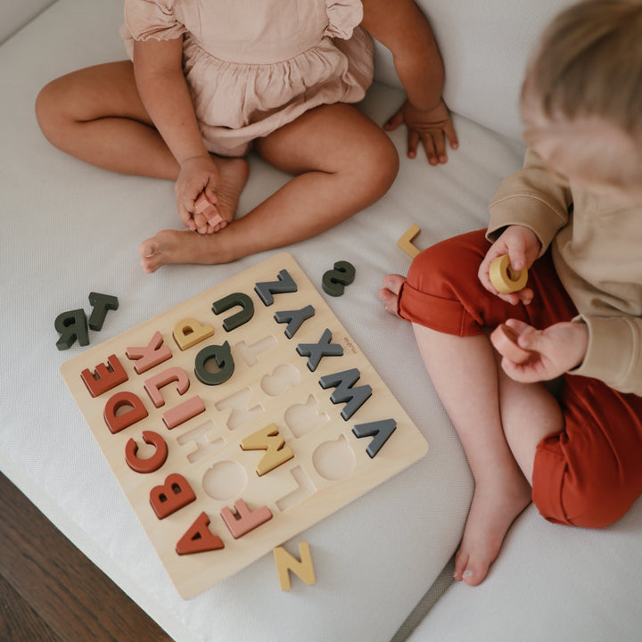Children playing with a Mushie wooden puzzle