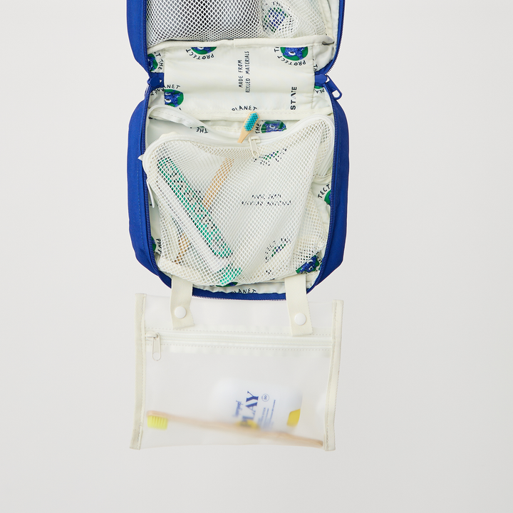 Lower compartment of a packed Bensen with toothpaste in the mesh pocket and the clear pouch below