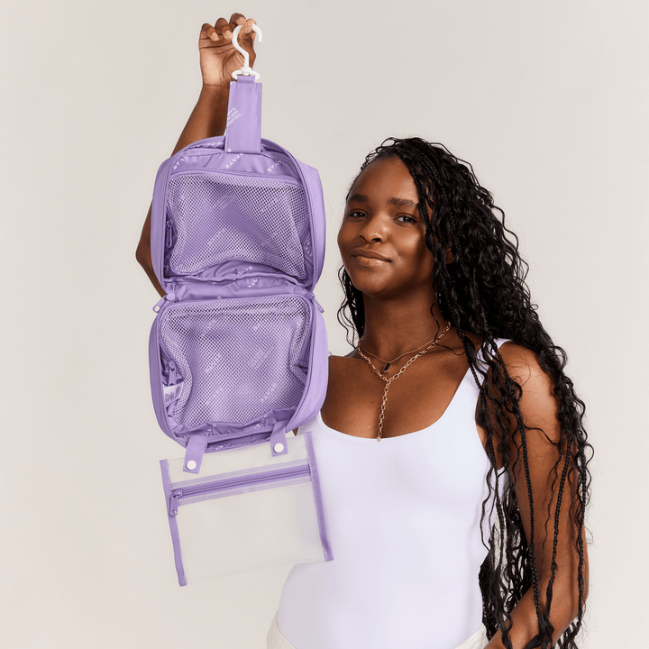 Model holding an opened lilac Bensen toiletry bag by its hook to show the hanging layout