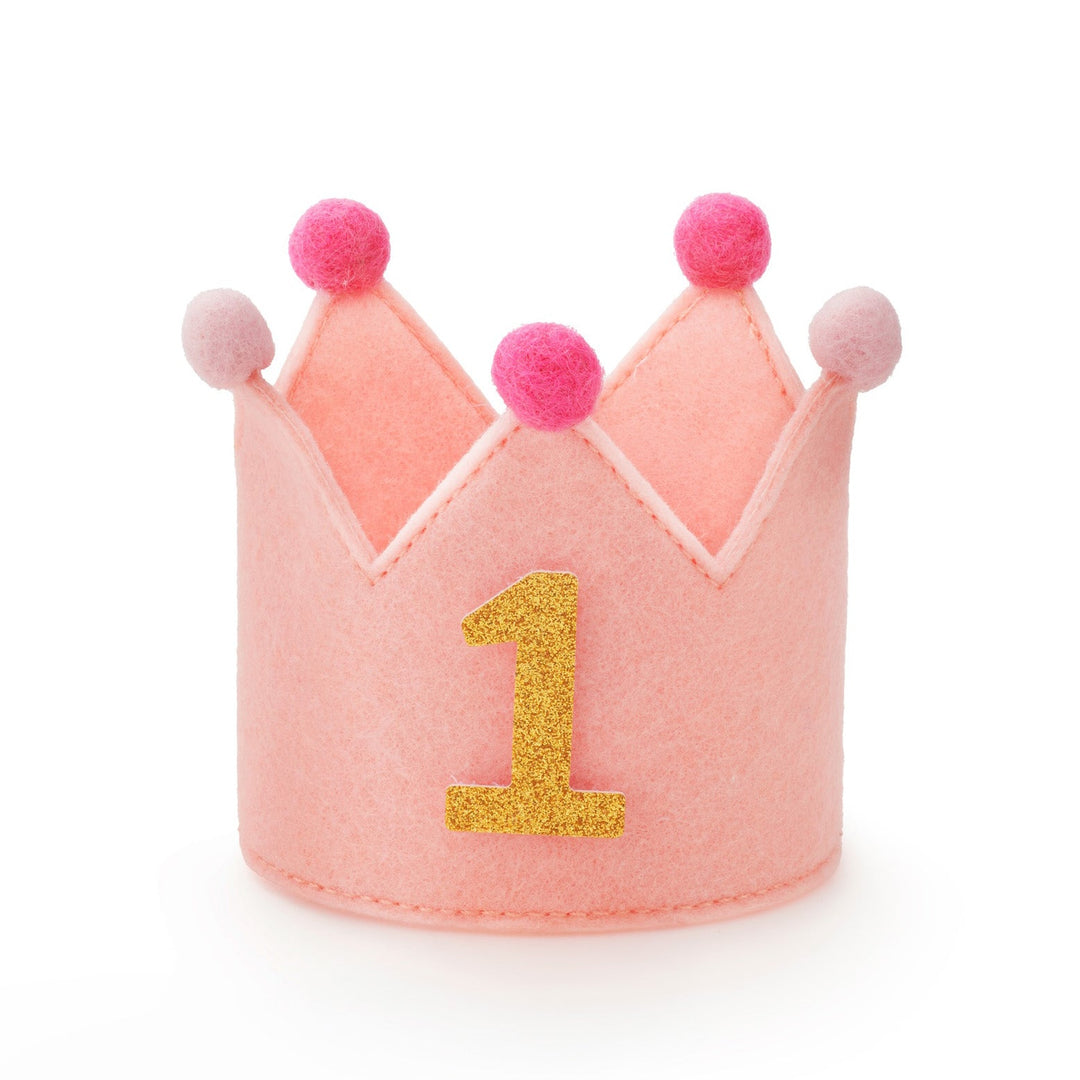 Blush pink felt dog birthday crown with pink pom-poms and a gold glitter number 1, front view on white