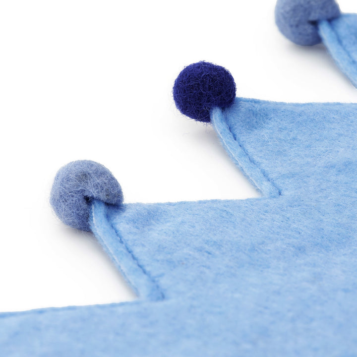 Close-up of the light blue felt crown points finished with navy and periwinkle pom-poms