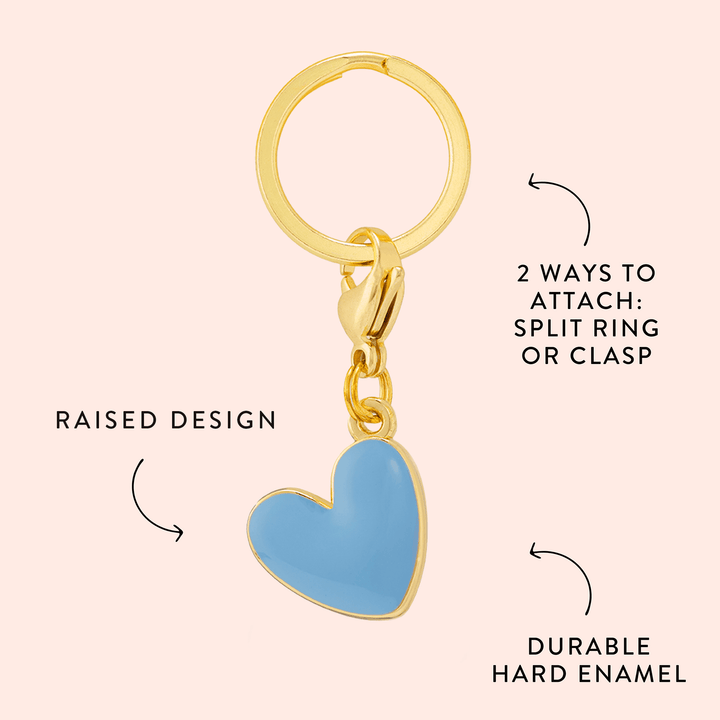 Blue heart charm callout on blush pink noting the raised design, hard enamel, and two ways to attach