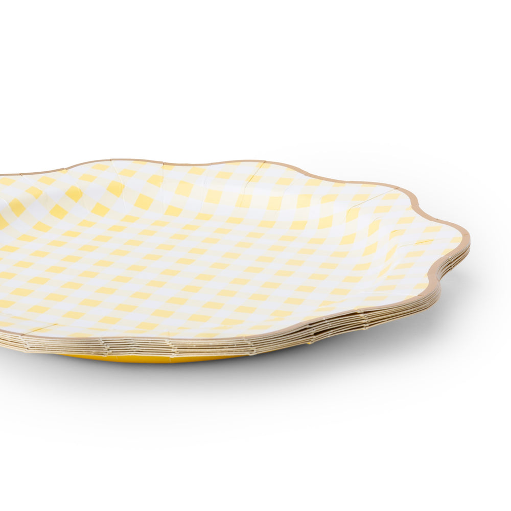 A stack of scalloped-edge paper plates with a yellow and white gingham check pattern and a gold rim, shown on a white background.