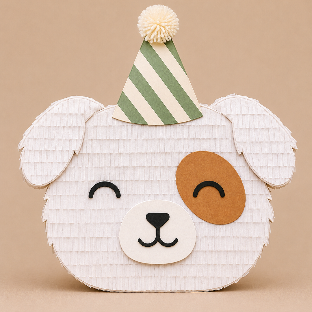 White puppy face piñata with a brown eye patch, floppy ears, and a green striped party hat, for a puppy birthday party