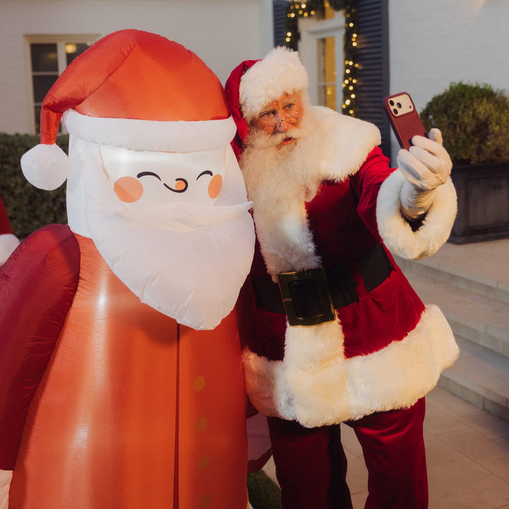 Person dressed as Santa taking a selfie with the inflatable vintage Santa