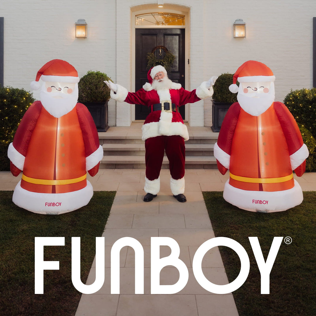 Two inflatable vintage Santas flanking a front door with a person dressed as Santa
