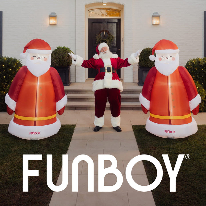 Two inflatable vintage Santas flanking a front door with a person dressed as Santa