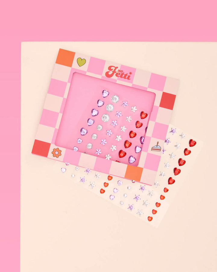 Card of red heart, white daisy, and clear rhinestone eye gems shown at an angle