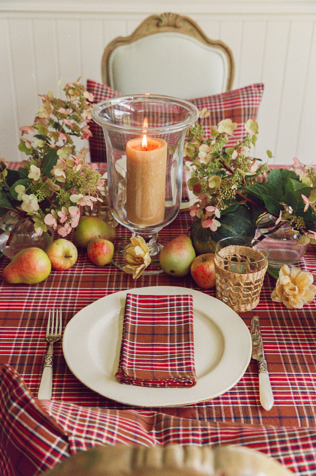 Charlotte plaid tablecloth with a cream plate, pillar candle, and pears at a place setting