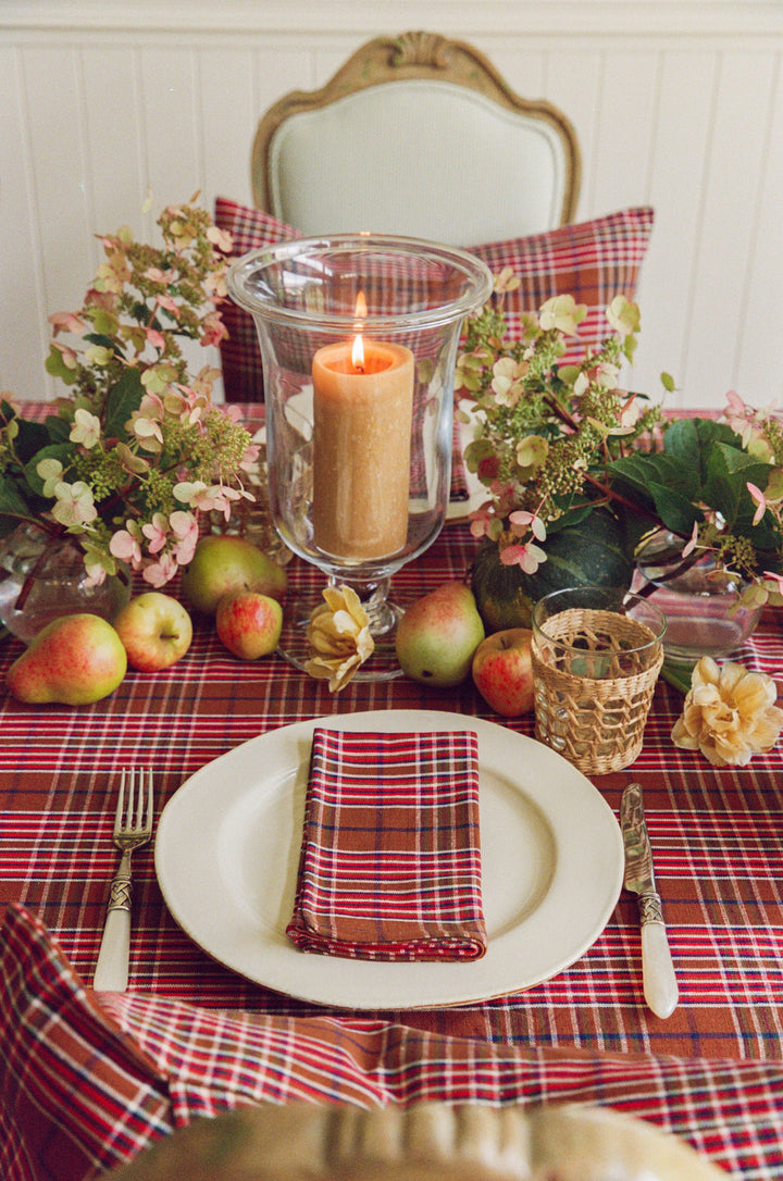 Charlotte plaid tablecloth with a cream plate, pillar candle, and pears at a place setting