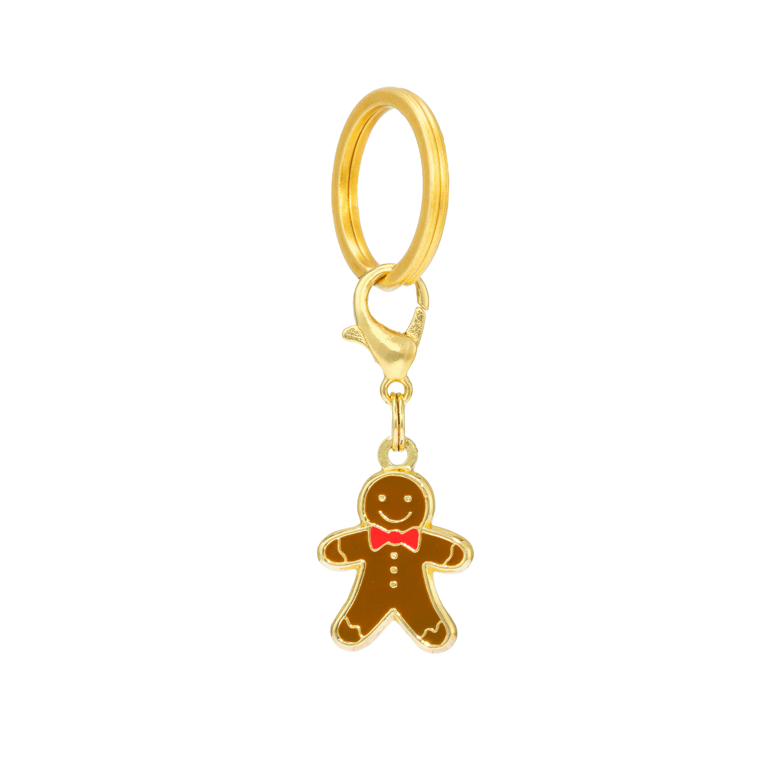 Smiling brown gingerbread collar charm with a red bow tie, suspended from a gold clasp and split ring on white.