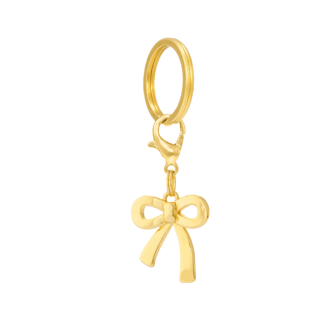 Gold bow dog charm hanging from a split ring and lobster clasp