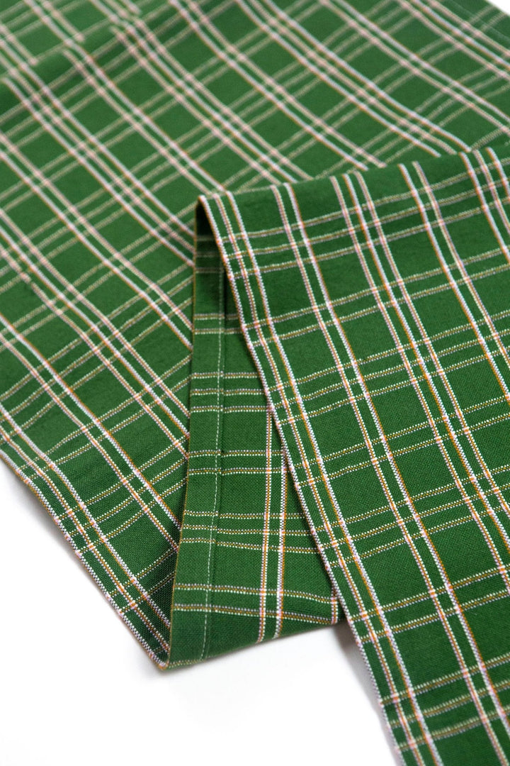 Close-up of forest green handwoven cotton plaid with ochre and lilac threads