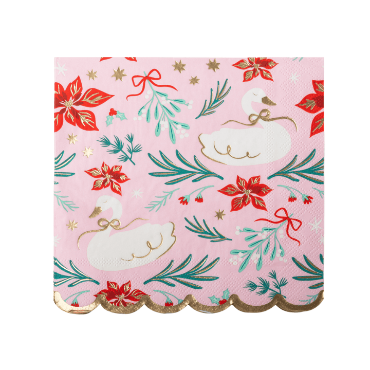 A square pink paper napkin with a scalloped gold edge, featuring a festive holiday pattern of white swans, red poinsettias, green pine branches, and gold stars.