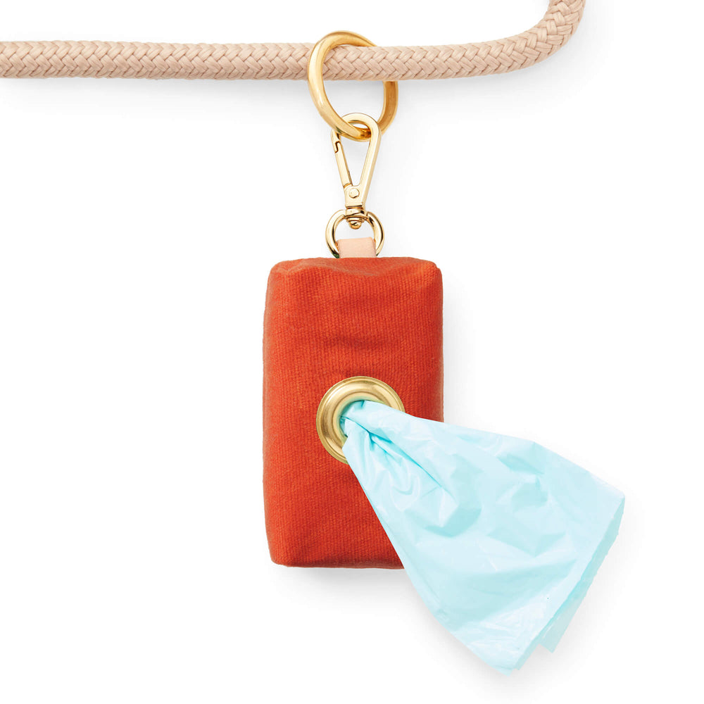 Rust canvas holder on a rope leash with a mint poop bag pulled through the brass grommet