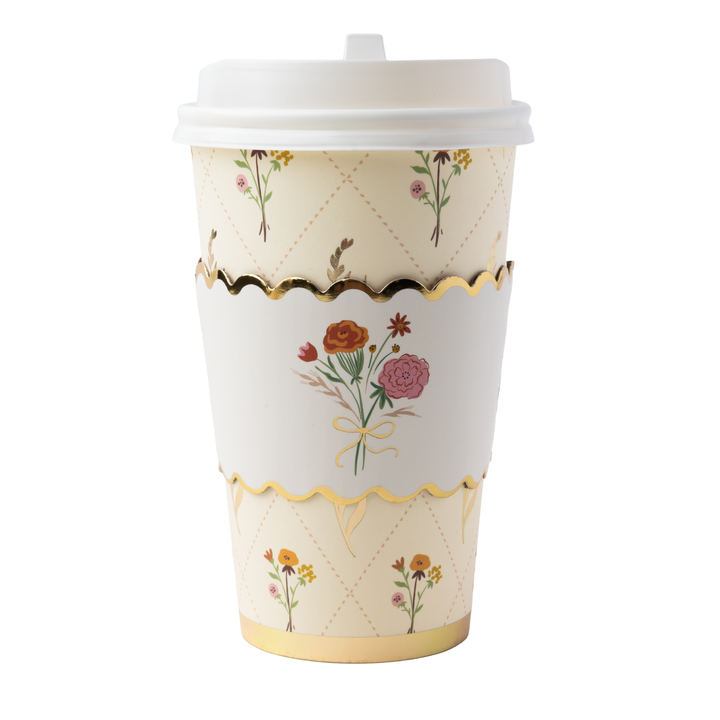 A set of paper disposable cups and napkins with a cream background, gold scalloped borders, and a delicate floral pattern. 