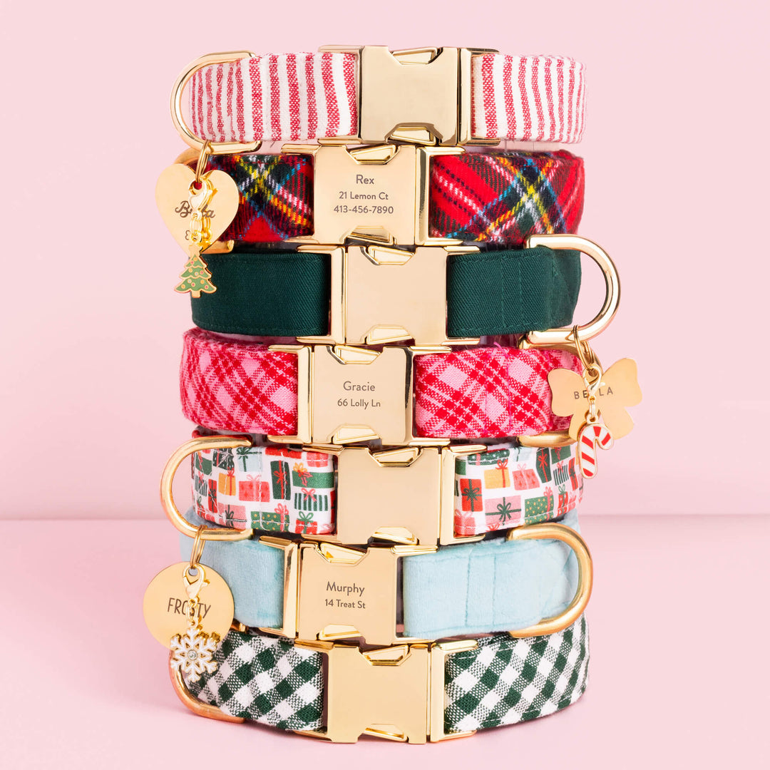 Stack of holiday dog collars in tartan, stripe, gingham, and green with gold tags and charms