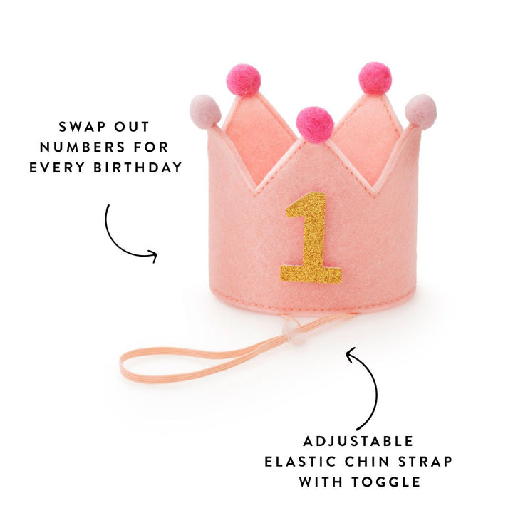 Blush crown with gold 1 and peach chin strap, callouts for swappable numbers and the toggle