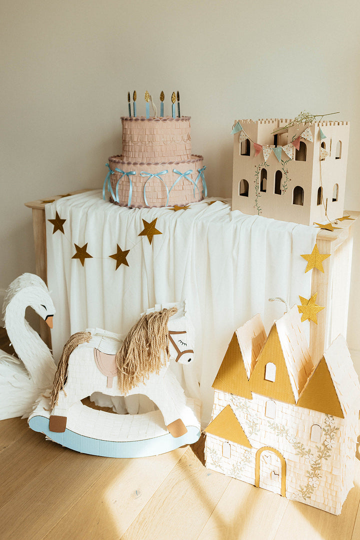 Children's play area with pinatas for a birthday party toys and a cake on a table