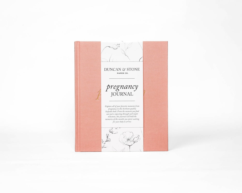 Blush pink Pregnancy Journal in its printed paper band standing upright, a gift for a baby shower