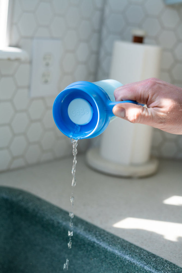 Hand tipping the Wonder Cup over a sink to show the auto-close valve