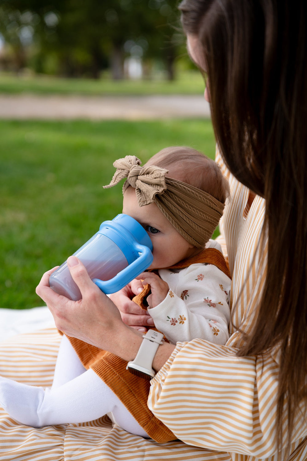 Parent holding a baby who is drinking from the blue Wonder Cup
