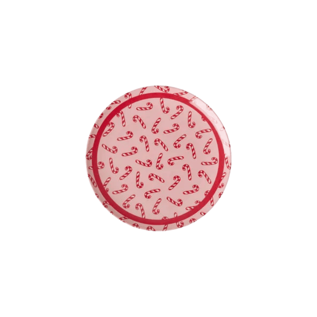 Small round pink melamine cake plate with red and white candy canes and a red rim, top view on white