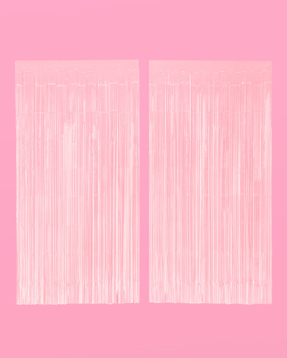Two matte pink foil fringe curtain panels hung side by side on a pink wall