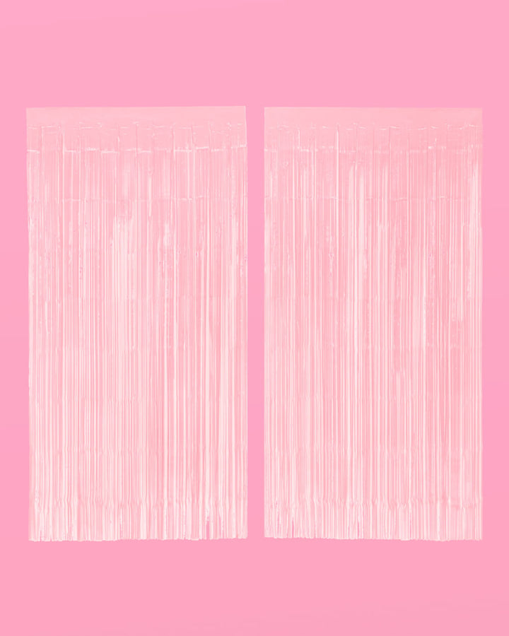 Two matte pink foil fringe curtain panels hung side by side on a pink wall