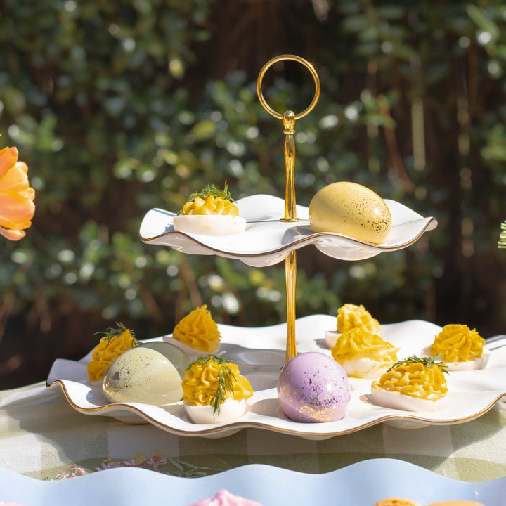 Tiered platter filled with deviled eggs and pastel eggs on an outdoor Easter table