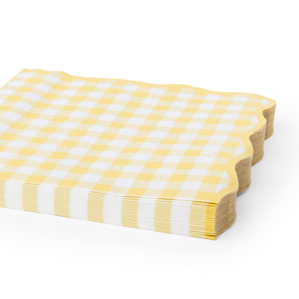 Yellow and white gingham check paper napkins with scalloped edges, shown on a clean white background.A stack of yellow and white gingham check paper napkins with scalloped edges.