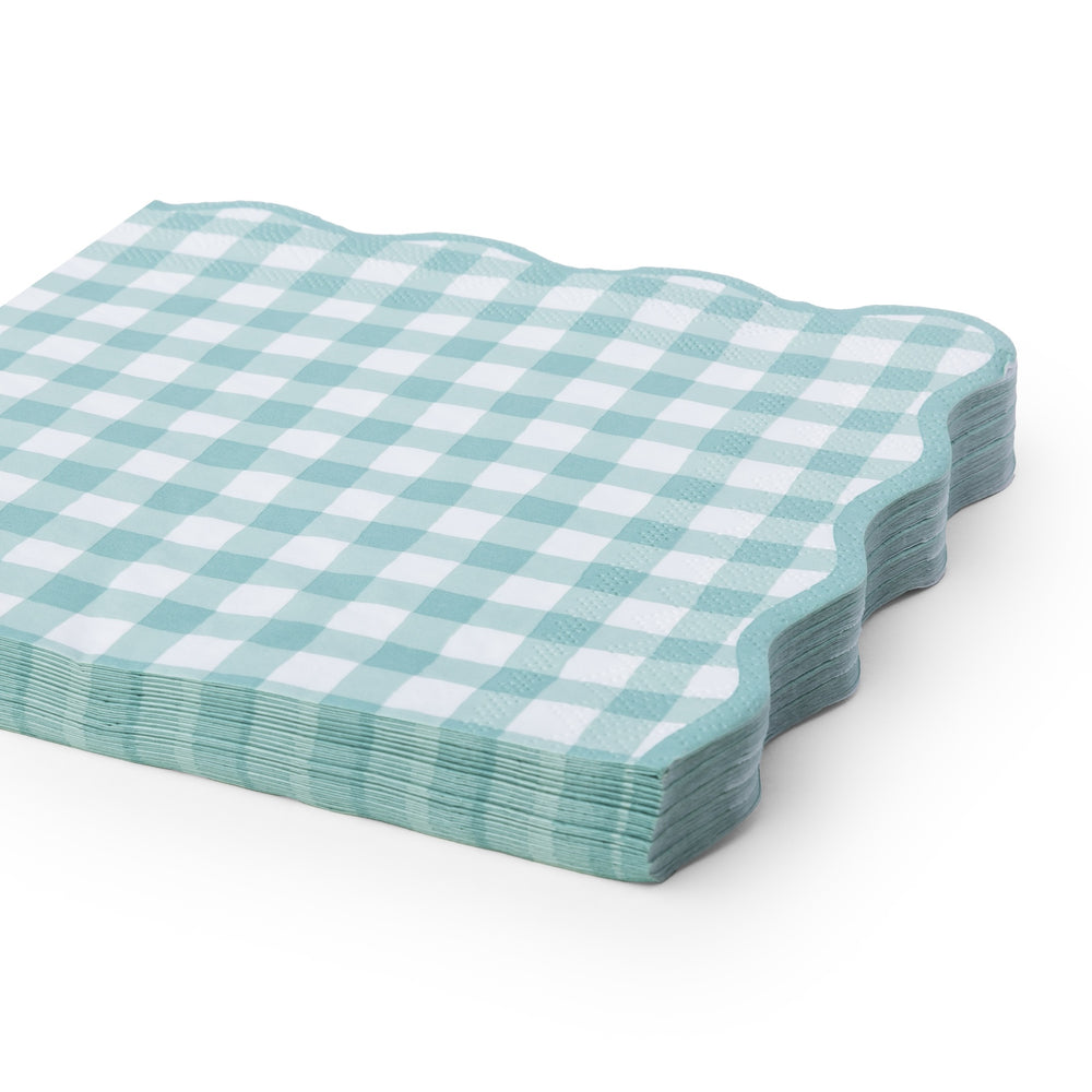 A stack of square paper napkins with a light sage and white gingham check pattern and scalloped edges, shown on a clean white background.