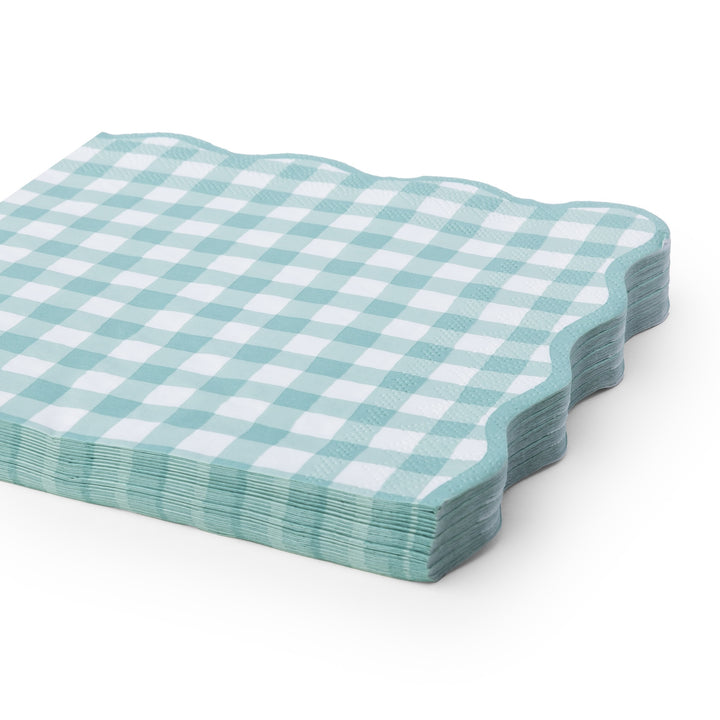 A stack of square paper napkins with a light sage and white gingham check pattern and scalloped edges, shown on a clean white background.