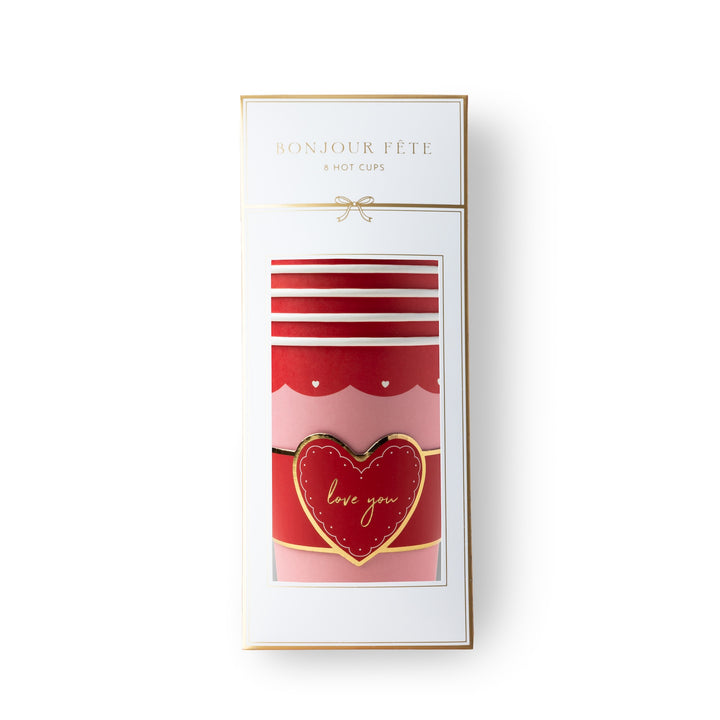 A boxed set of red and pink striped hot cups with a gold heart-shaped 'love you' emblem, presented in a white package labeled 'BONJOUR FÉTE 8 HOT CUPS' on a white background.