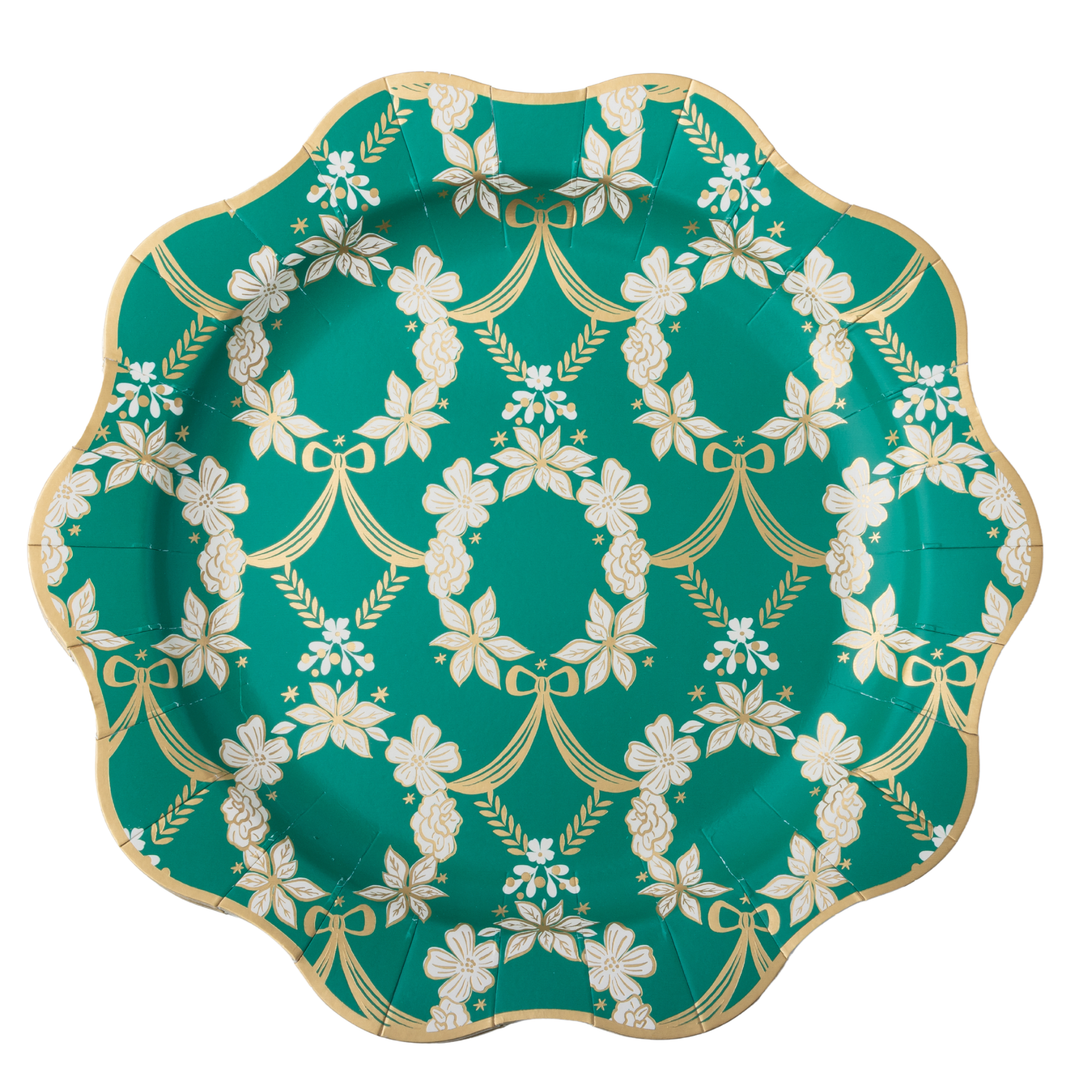 A scalloped paper plate featuring a teal green background with a repeating white floral wreath pattern and a metallic gold border.