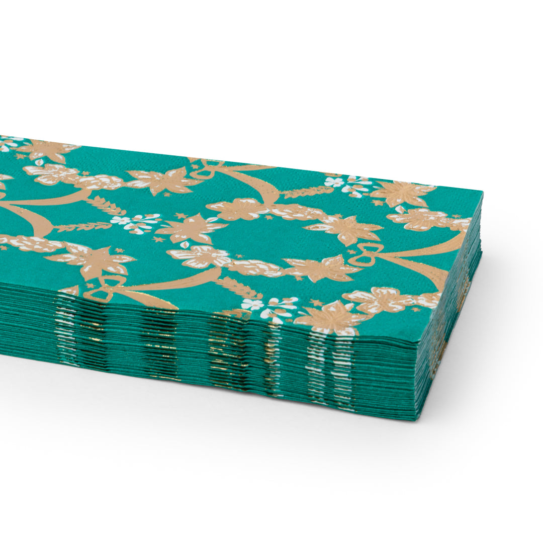 A stack of emerald green paper napkins with a gold floral vine pattern, photographed on a clean white background.