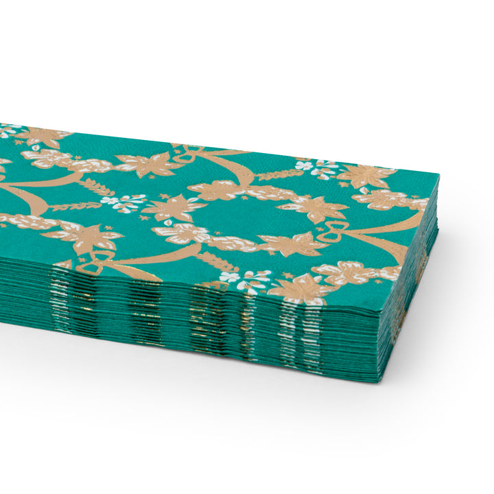 A stack of emerald green paper napkins with a gold floral vine pattern, photographed on a clean white background.