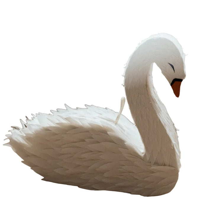White swan figurine pinata  on a wooden floor with a light background