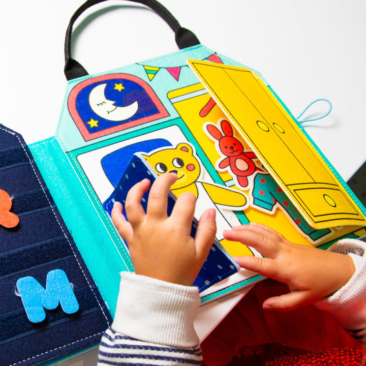 Child playing with felt Montessori activity kit pieces including a letter and a closet