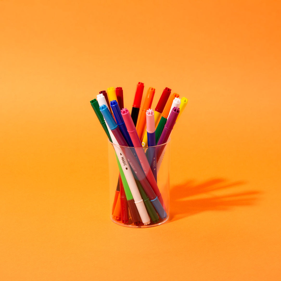 Color-changing magic markers standing in a cup on an orange background