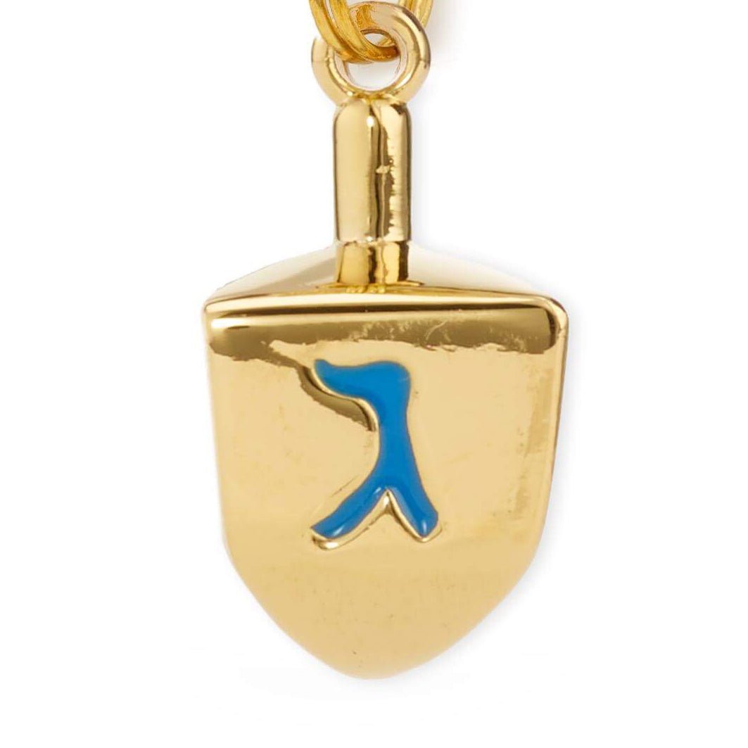 Close-up of the gold dreidel face showing the glossy finish and blue enamel letter