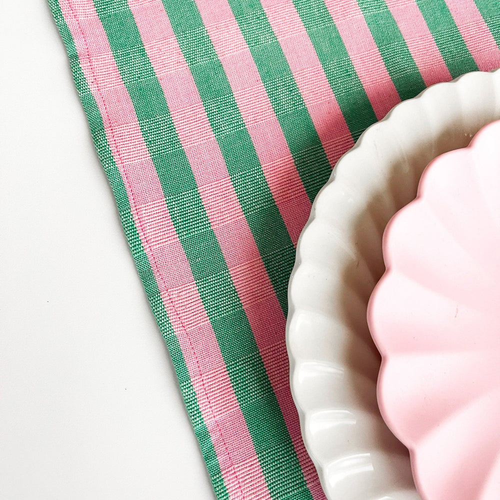 Close-up of the green and pink stripe cotton runner under a pink scalloped plate for a spring party