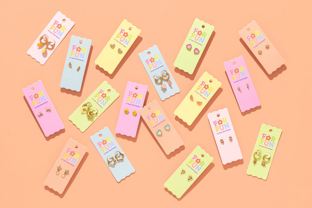 Flat lay of For Fun tween earring cards including pizza slice studs on peach