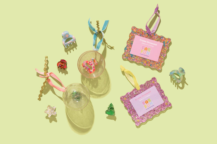 Flat lay of holiday claw clips, glitter ball ornaments, and two glitter frame ornaments on chartreuse