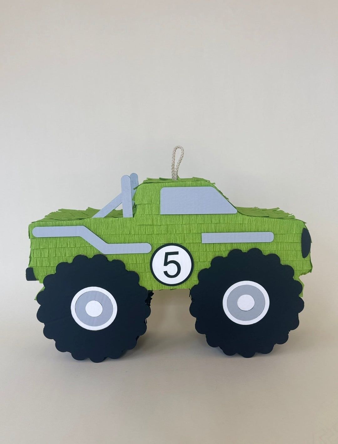 Green monster truck piñata with a number 5 on the door and oversized black wheels, for a monster truck birthday