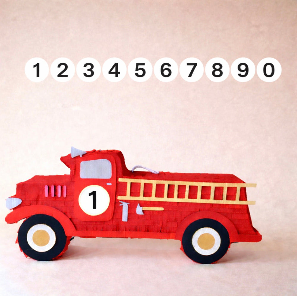Red fire truck-shaped Pinata with a ladder on a beige background