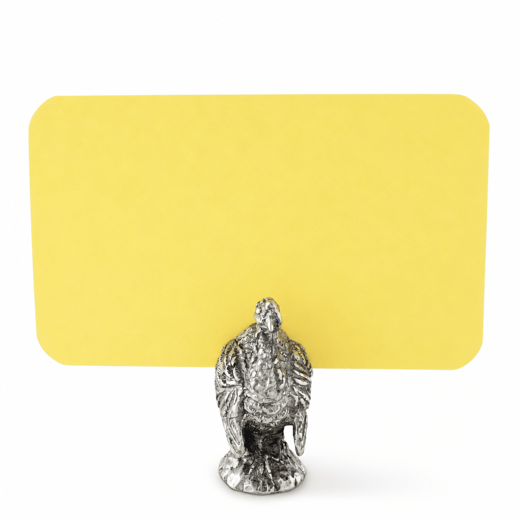 Pewter turkey place card holder on a round base holding a blank yellow place card
