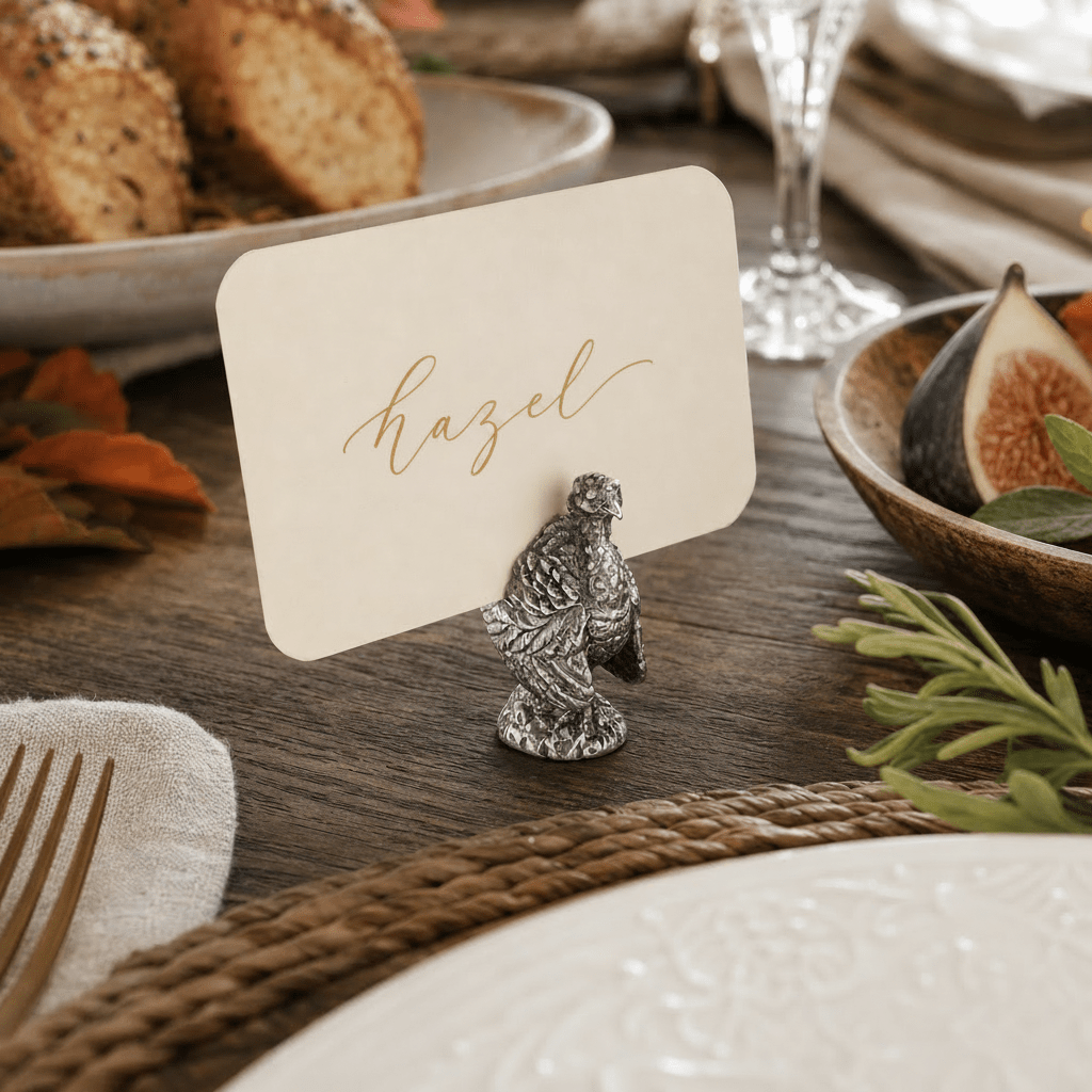 Pewter turkey holding a cream place card with the name Hazel on a Thanksgiving table with figs